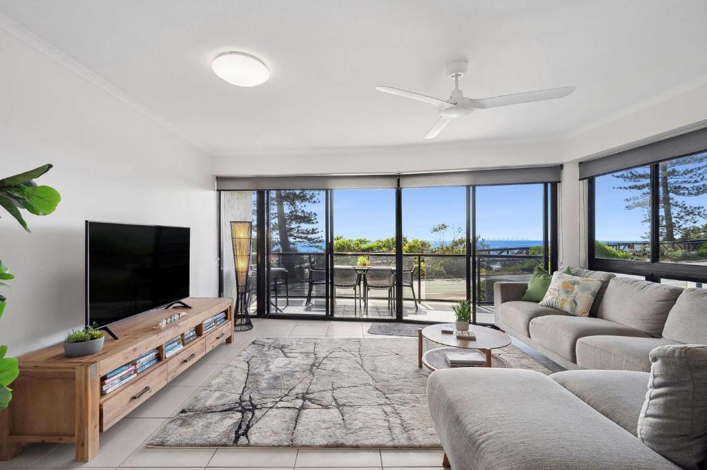 a living room with a couch and a flat screen tv at Unit 1 Phoenix in Coolum Beach