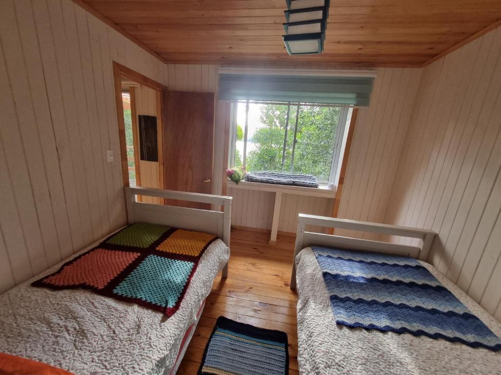 2 camas en una habitación pequeña con ventana en Cabaña en Contulmo, en Contulmo