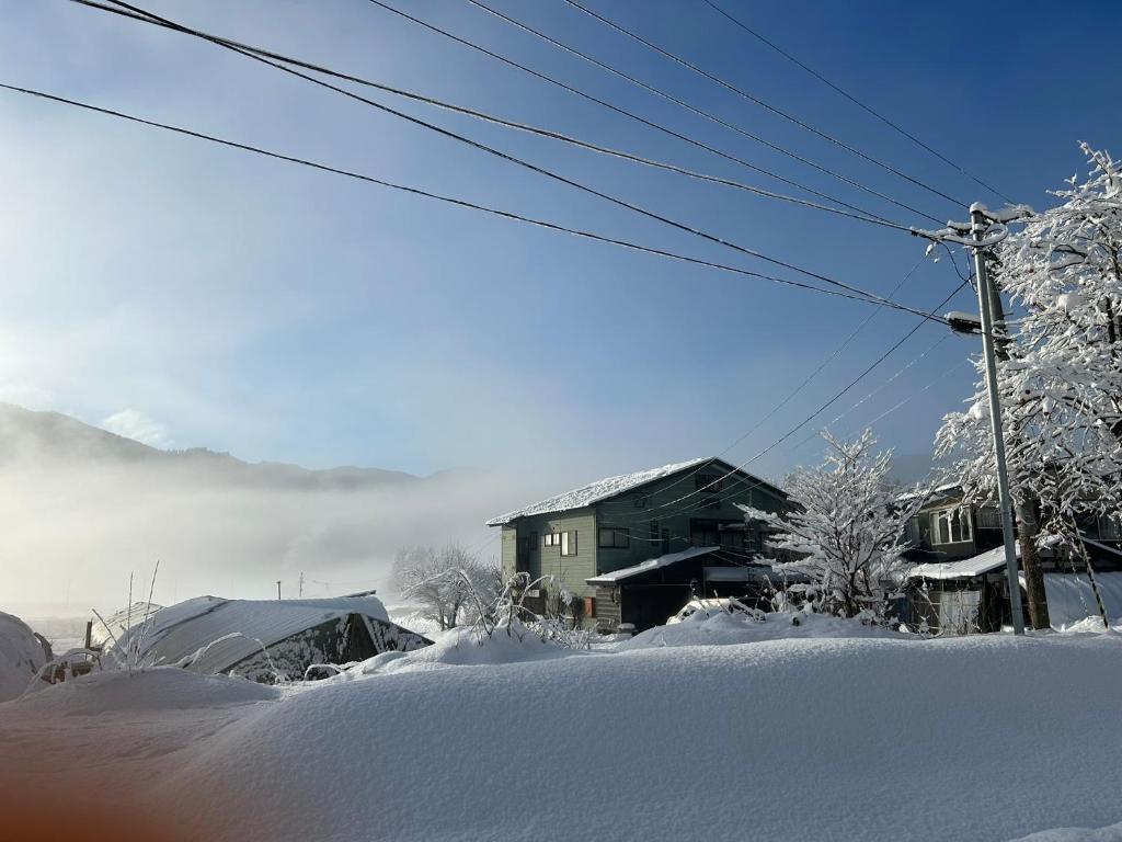 une maison dans la neige avec des arbres enneigés dans l'établissement noukanoyado seisetsukan, à Senboku