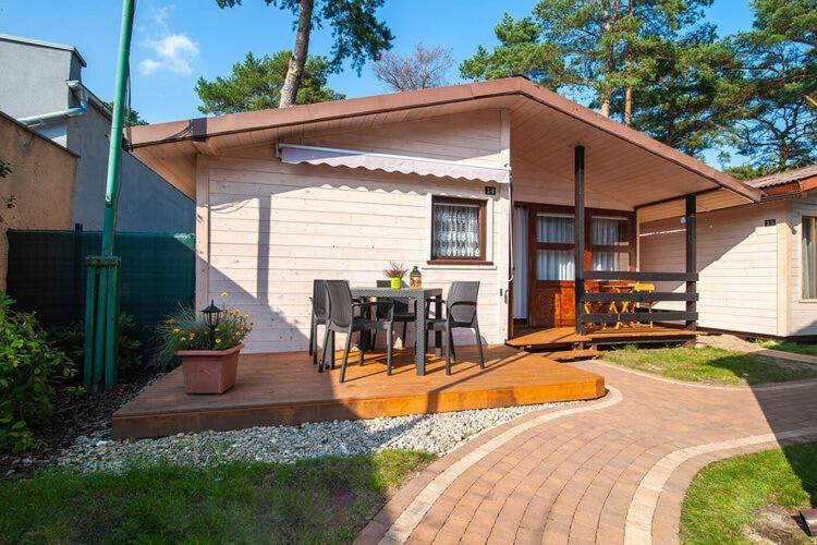 een klein huis met een tafel en stoelen op een patio bij Holiday cottages, sauna, whirlpool, Mrze yno in Mrzeżyno