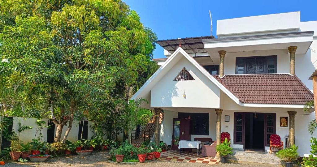 a white house with trees in front of it at Alma Homestay in Mararikulam