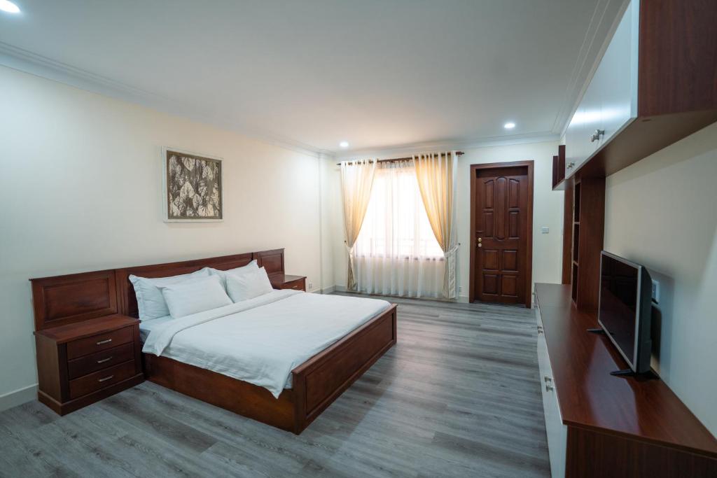 a bedroom with a bed and a flat screen tv at HAMPTONS Apartments in Phnom Penh