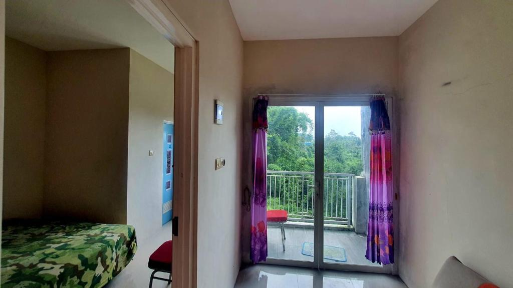een kamer met een bed en een balkon met een raam bij NK Villa Syariah Batu in Batu
