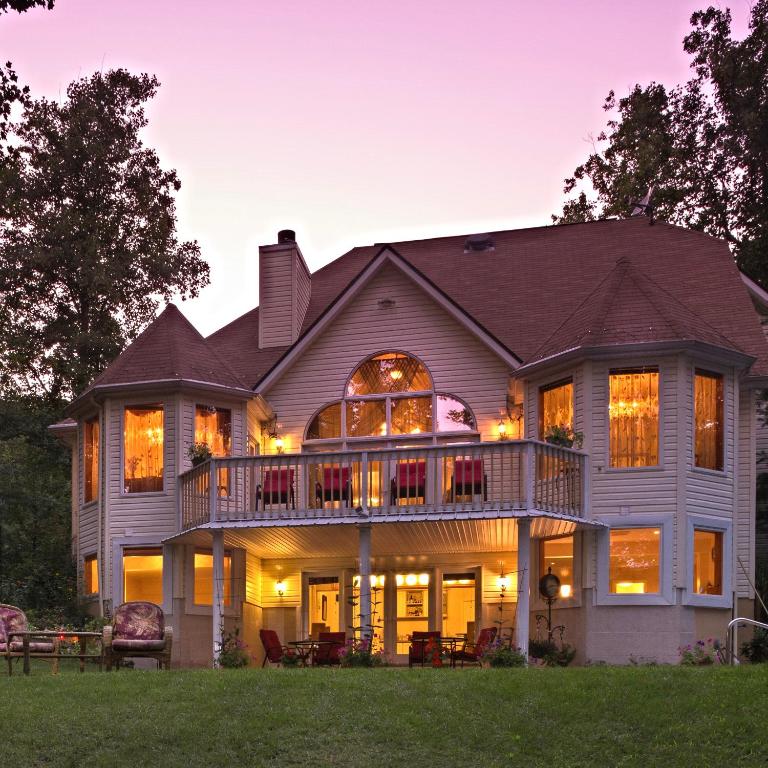 a large house with a wrap around deck at dusk at Cherry Valley Manor in Stroudsburg
