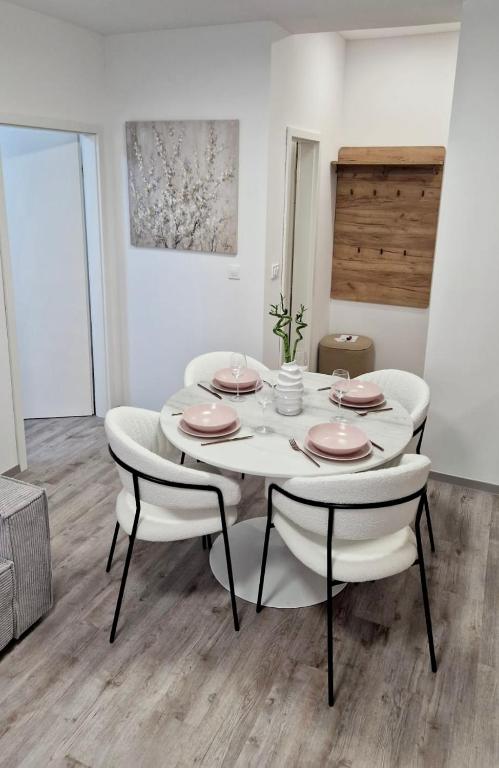 uma sala de jantar branca com uma mesa e cadeiras brancas em Central Cute City Apartment w Free Parking em Ljubljana