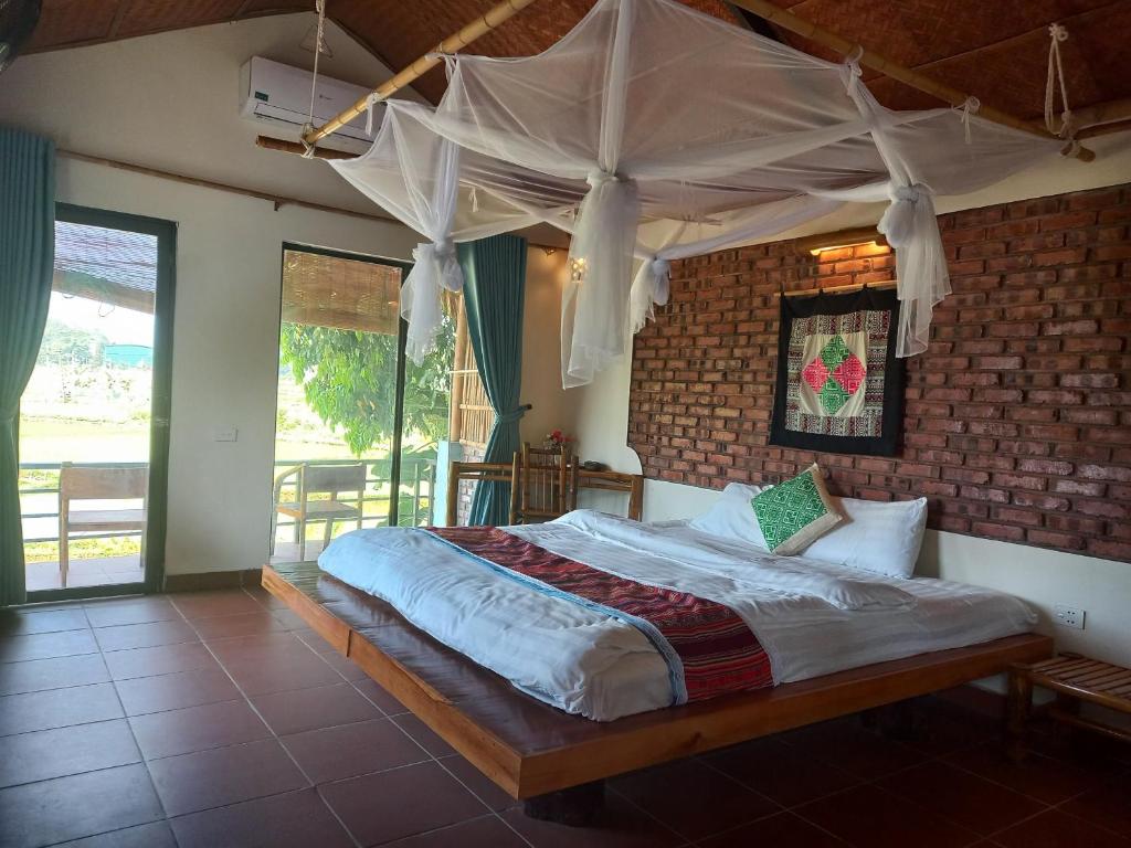 ein Schlafzimmer mit einem großen Bett in einer Ziegelwand in der Unterkunft Mai Chau Green house in Mai Châu