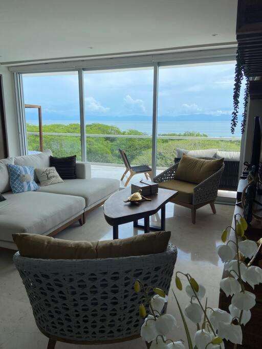a living room with a couch and chairs and a large window at Increíble departamento en Bolongo punta de mita in Higuera Blanca