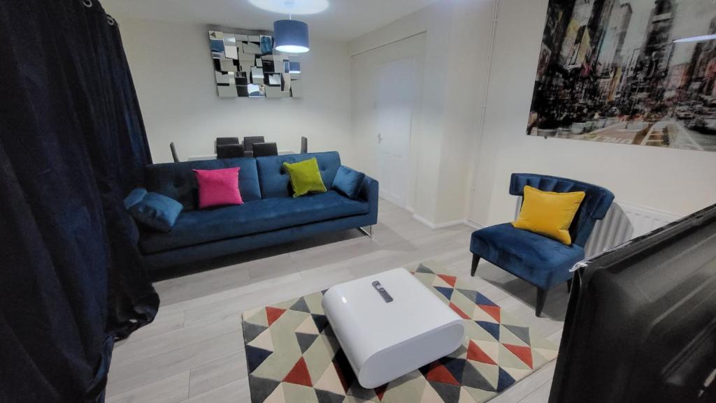 a living room with a blue couch and two chairs at Garland Modern Close To Station 3 Bedroom City Apartment in London