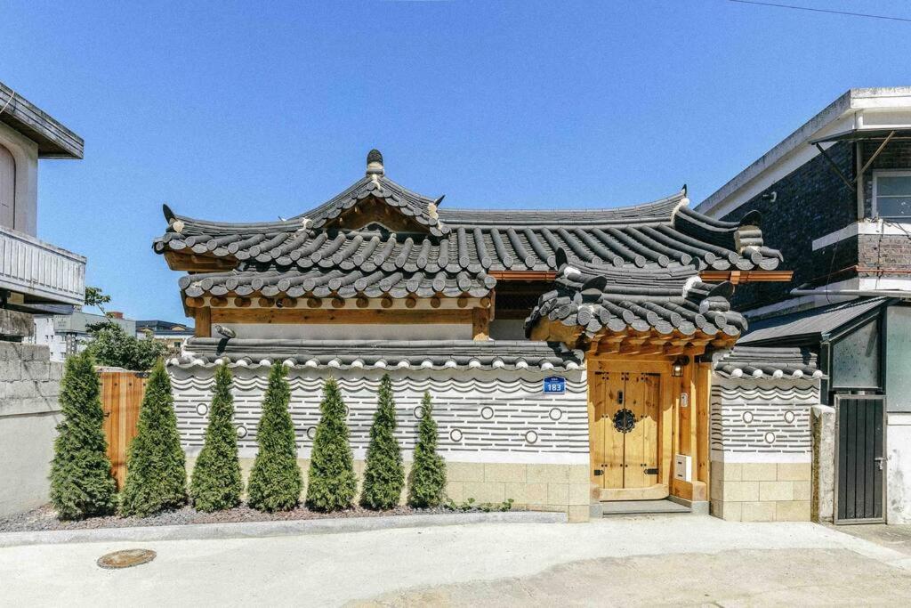 a building with an asian roof with trees in front of it at Hongsi Art House in Gongju
