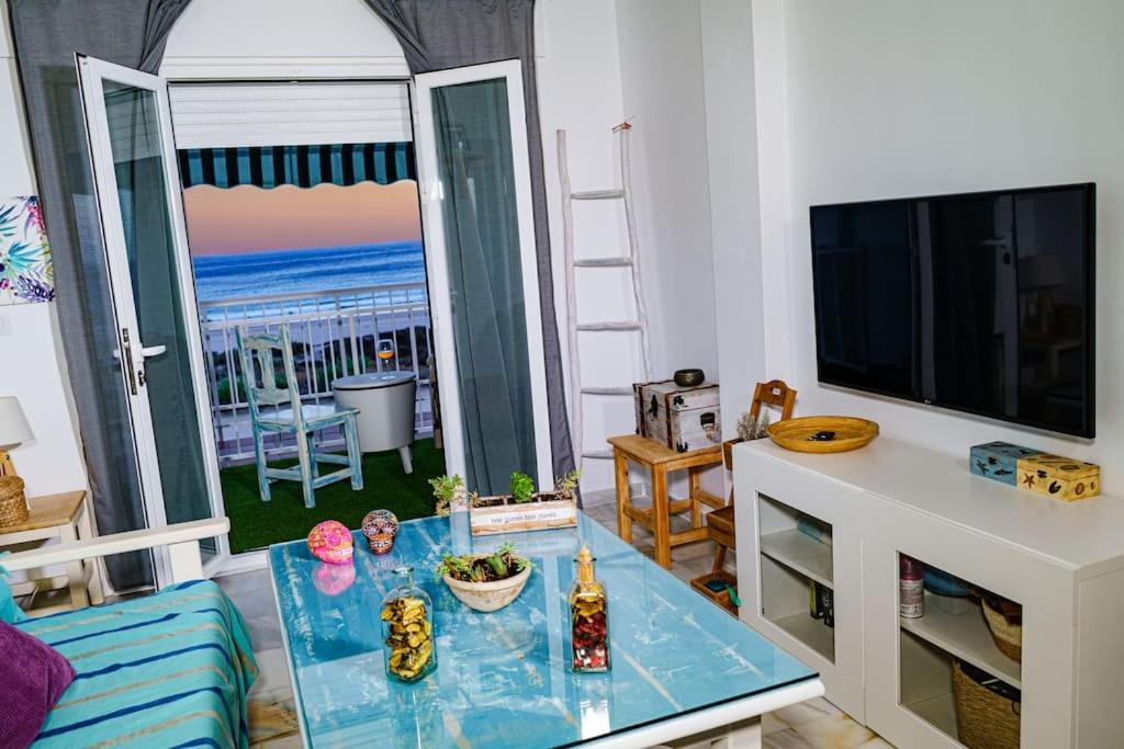 ein Wohnzimmer mit Tisch und Blick auf das Meer in der Unterkunft Apartamento con inmejorables vistas de la Barrosa in Chiclana de la Frontera