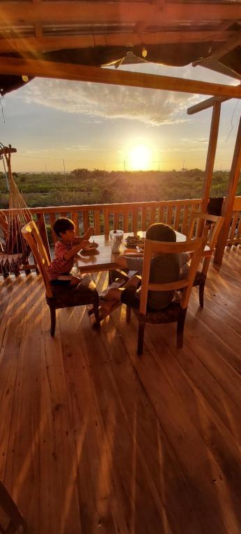 un joven sentado en una mesa en una terraza de madera en House Beach, en Puerto Cayo