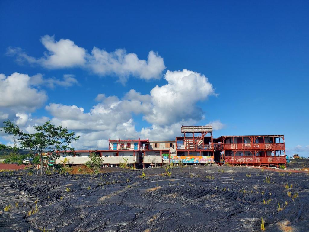 a group of buildings with a blue sky and clouds at Open Gate Hostel Hawaii in Pahoa