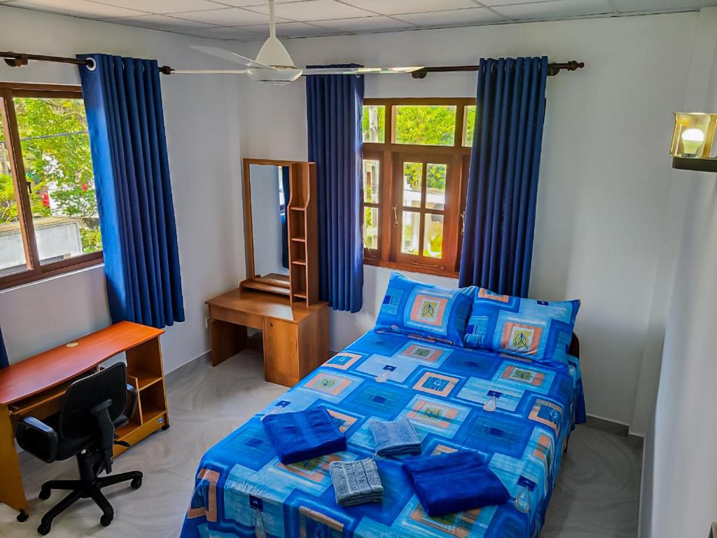 a bedroom with a bed and a desk and window at Shalom Villa in Rajagiriya