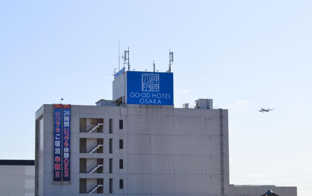 a building with a blue sign on top of it at グッドホテル大阪 in Toyonaka