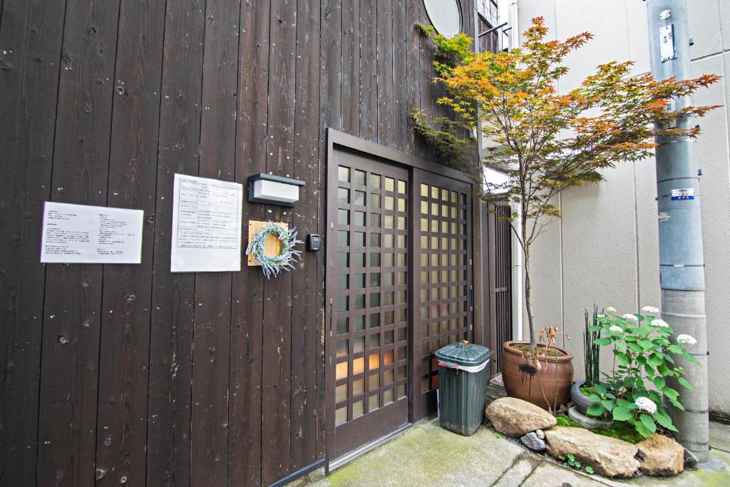 una recinzione di legno con una porta e un albero di -時の宿 上七軒- Kyoto Machiya 金閣寺周辺 a Kyoto