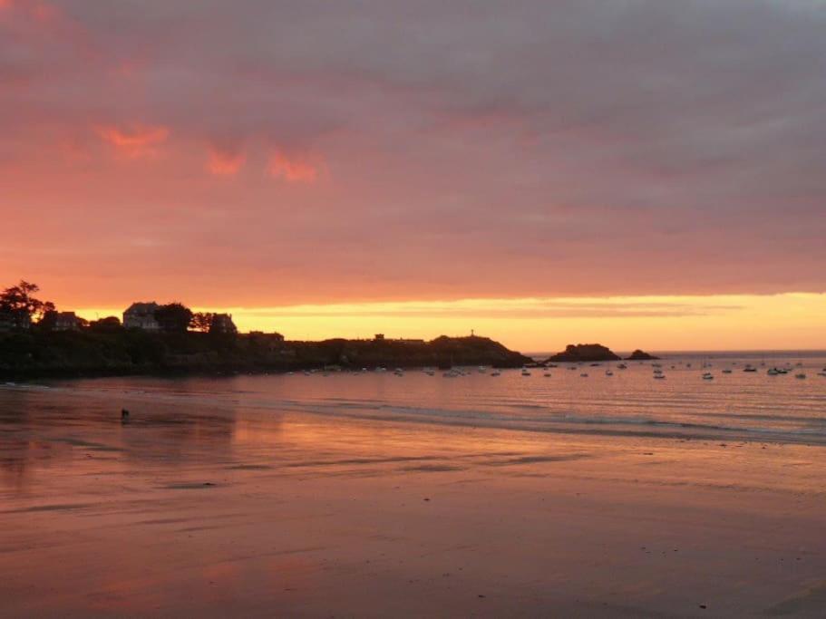 a sunset over a beach with boats in the water at Appartement 1 chambre terrasse 200m de la plage et GR34 in Saint-Lunaire