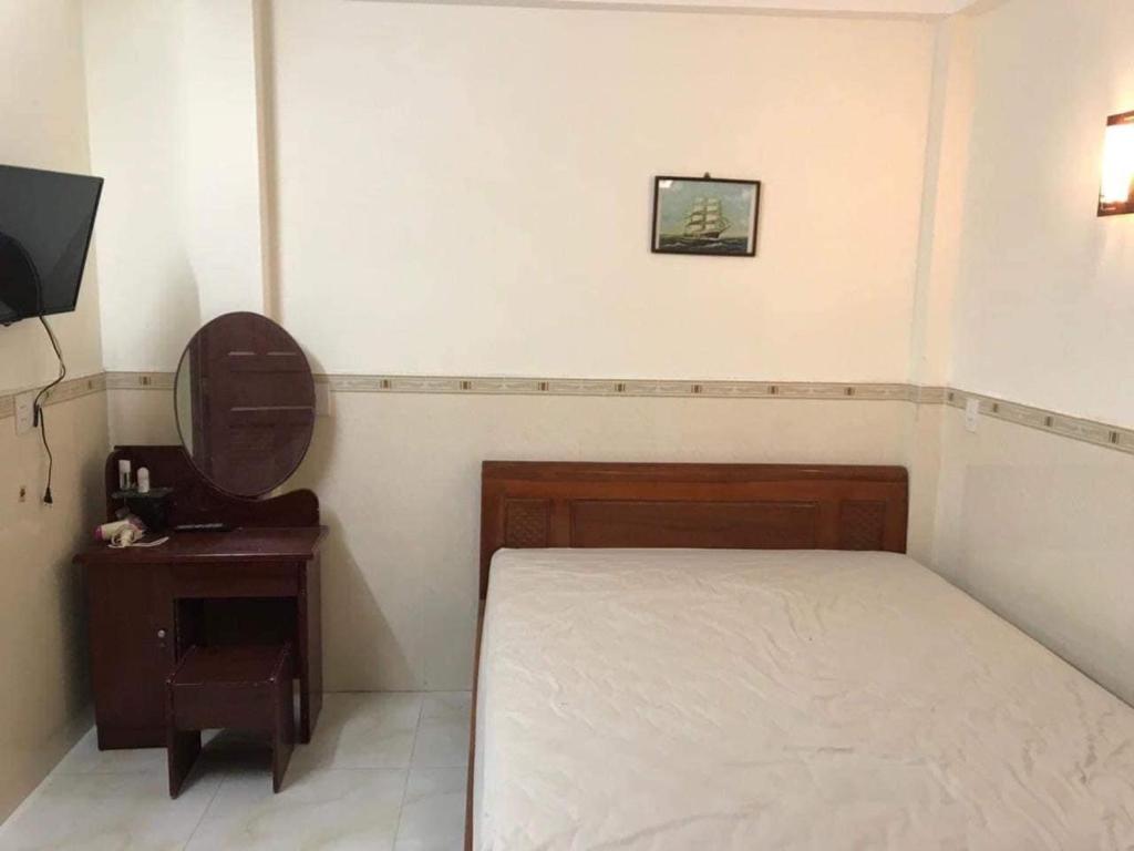 een slaapkamer met een bed, een tafel en een televisie bij Lazánia Homestay Hội An in Hội An