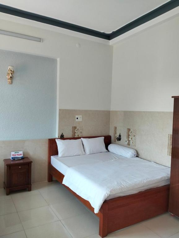 um quarto com uma cama grande e lençóis brancos em Khách sạn Thảo Trang em Quang Ngai