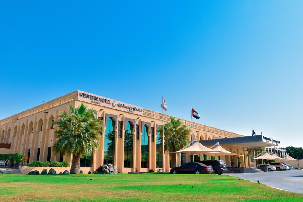 a large building with palm trees in front of it at Western Hotel - Ghayathi in Ghayathi