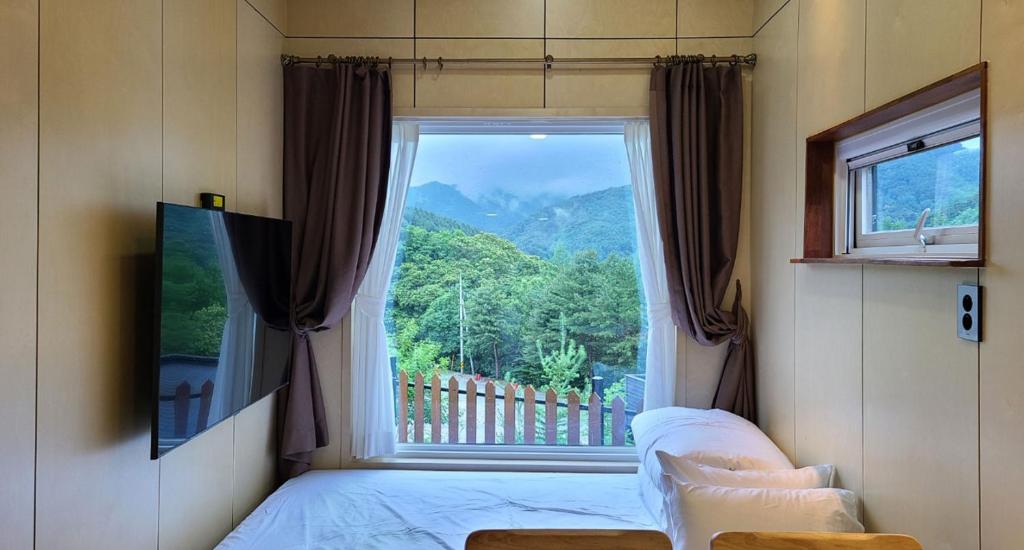 a bedroom with a large window with a mountain view at Starium Jecheon in Jecheon