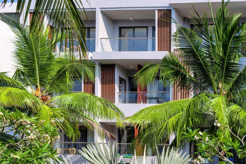 un edificio de apartamentos con palmeras delante en Hana Hotel Sonasea Night Market Phu Quoc en Phu Quoc