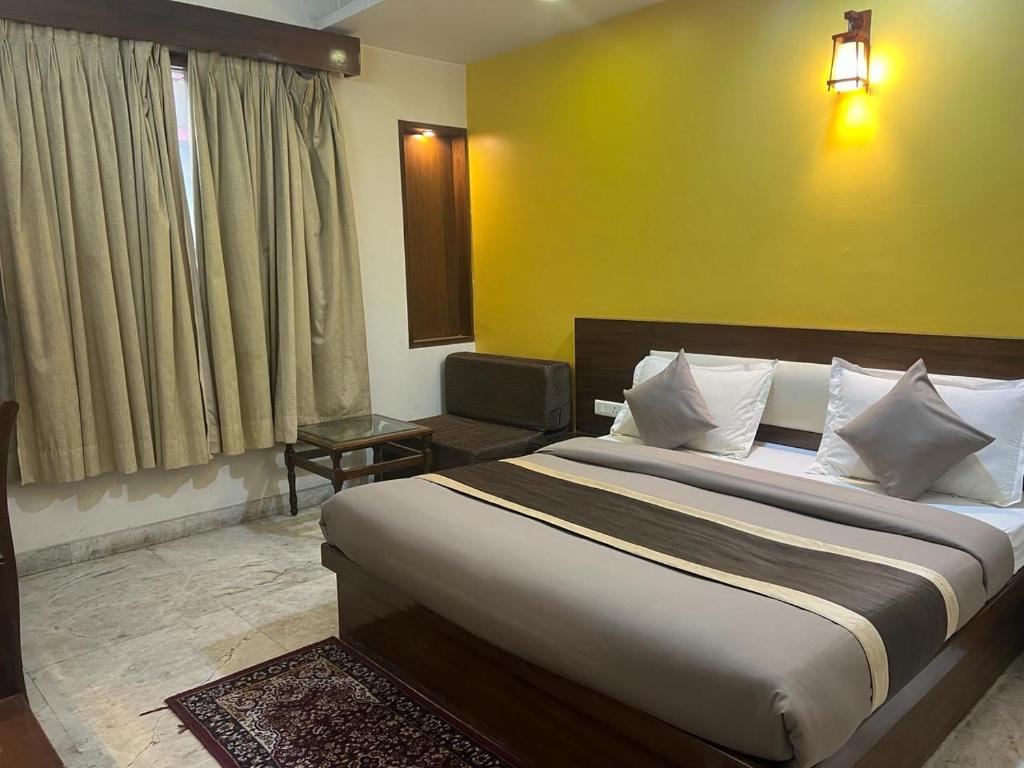 a bedroom with a large bed and a yellow wall at Svaruchi Inn in New Delhi