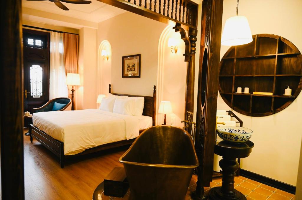 Schlafzimmer mit einem Bett, einer Badewanne und einem Spiegel in der Unterkunft La Belle Maison in Hanoi