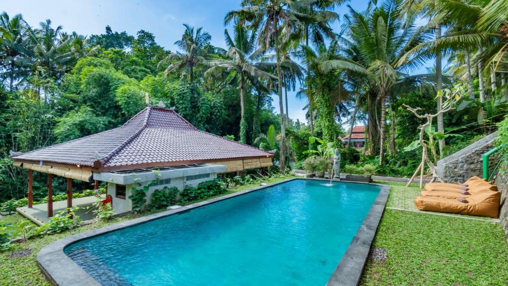 a swimming pool in front of a house with a gazebo at As I Am Ubud Retreat in Ubud