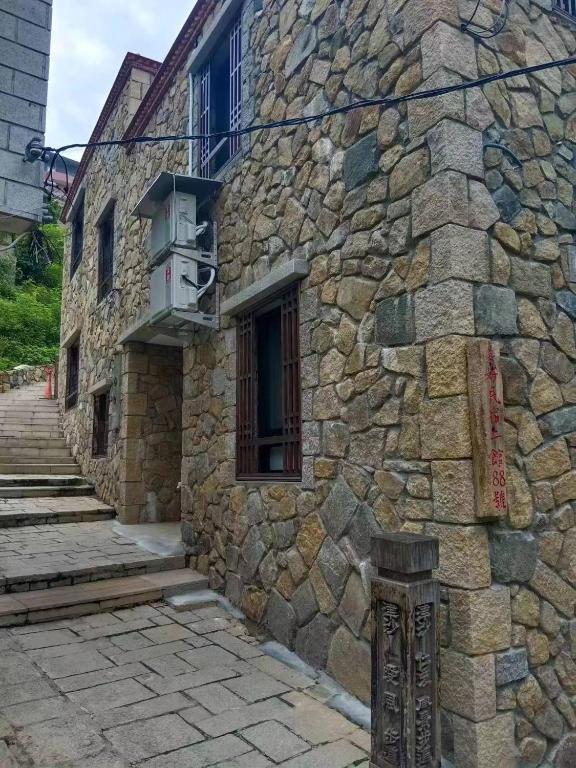 a stone building with a window and a balcony at Beautiful Guest House II in Chin-sha