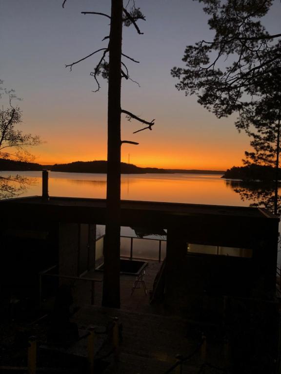 a sunset over a lake with a tree in the foreground at Rantahuvila Naantalissa in Naantali
