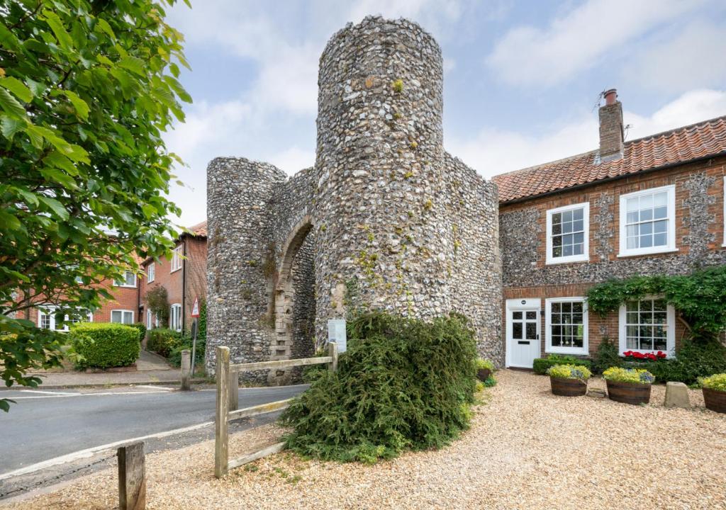 an old stone building with a fence in front of it at No.1 Baileygate Cottages in Castle Acre