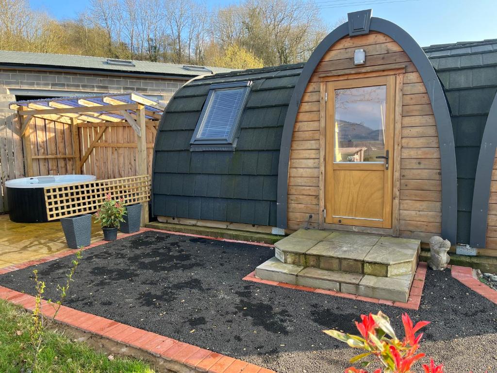 a small cabin with a wooden door in a yard at Squirrel Glamping Pod School House Farm in Leighton