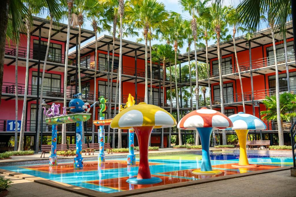 a building with a pool in front of a resort at Nongnooch Garden Pattaya Resort in Ban Nong Chap Tao