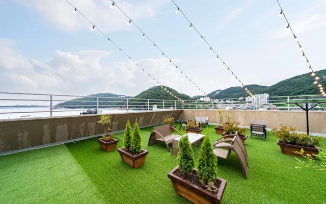 a balcony with a green yard with chairs and plants at Hotel Yaja in Geoje