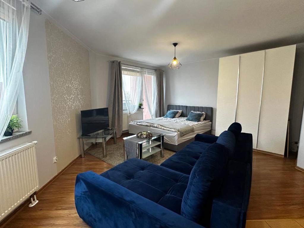 uma sala de estar com um sofá azul e uma cama em Apartament Studio Kamienna street em Breslávia