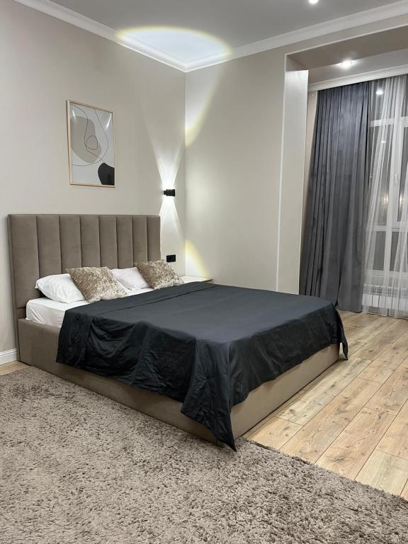 a bedroom with a large bed with a black blanket at Grand Champion Astana in Taldykolʼ