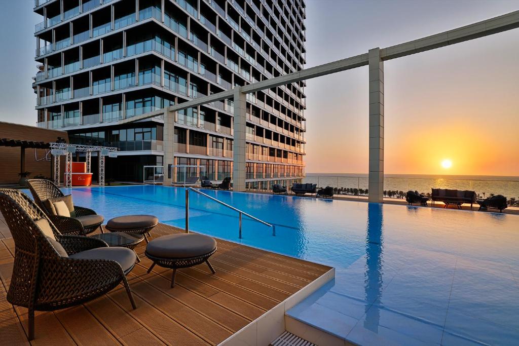 a large swimming pool with chairs and a building at Shangri-La Jeddah in Jeddah