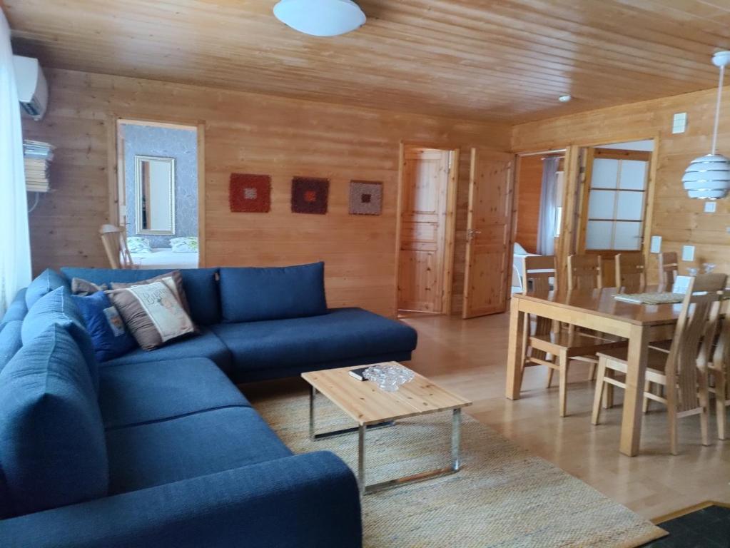 ein Wohnzimmer mit einem blauen Sofa und einem Tisch in der Unterkunft Lake Cottage Jänisvaara in Kolinkylä