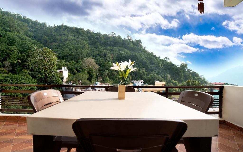 a table with a vase of flowers on a balcony at Yogvan Holidays 1BHK Apartments Tapovan Rishikesh in Rishīkesh