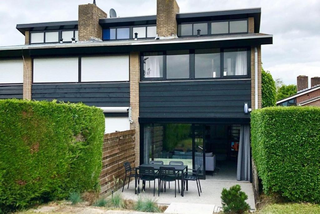 a black house with tables and chairs in front of it at De Woning, Wijk de Brabander 109 in Cadzand