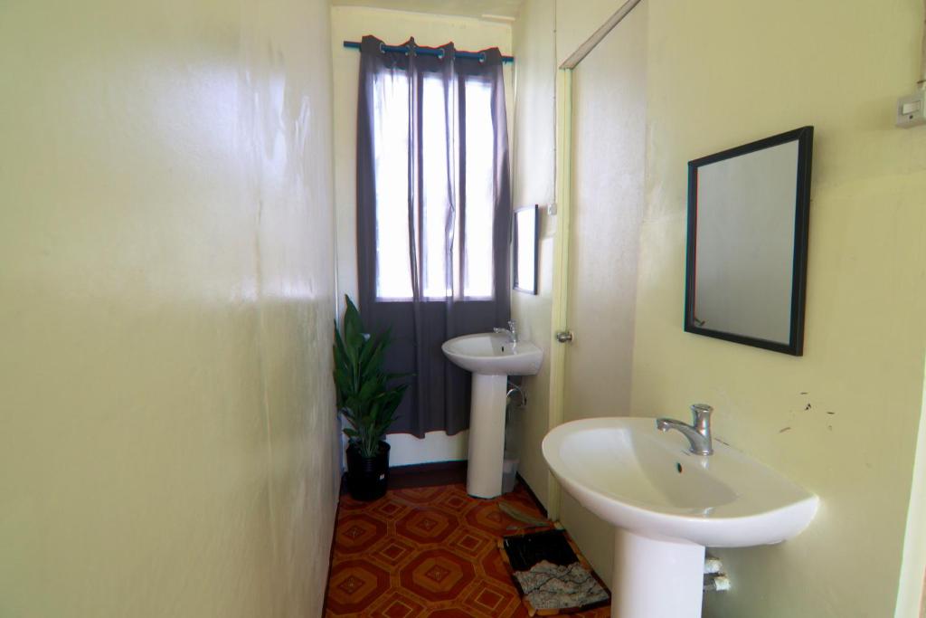a white bathroom with a sink and a mirror at Aloha Hostel Siargao in General Luna