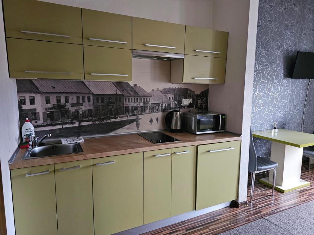 eine Küche mit gelben Schränken, einer Spüle und einer Mikrowelle in der Unterkunft Apart in Radomsko