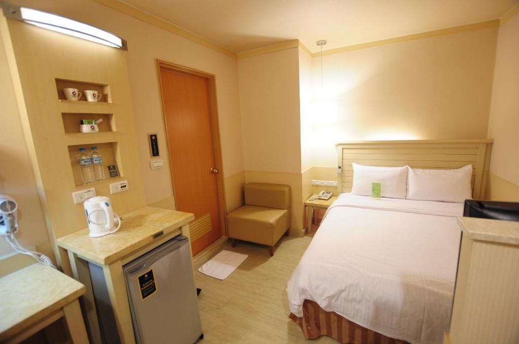 a small hotel room with a bed and a chair at Kindness Hotel - Tainan Minsheng in Tainan