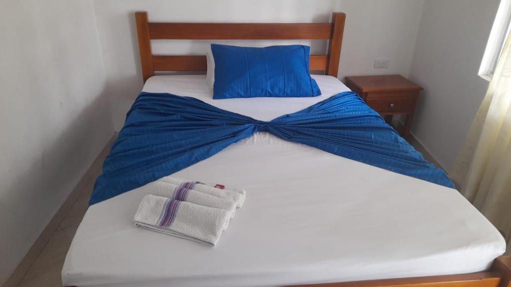 Una cama blanca con una corbata azul de moño. en Hotel Zarina en Villavicencio