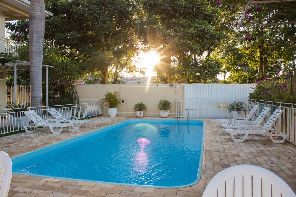 a swimming pool with chairs and a table at Pousada Cataratas in Foz do Iguaçu