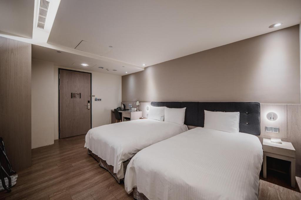 a hotel room with two beds with white sheets at Hub Hotel Kaohsiung Yawan Branch in Kaohsiung