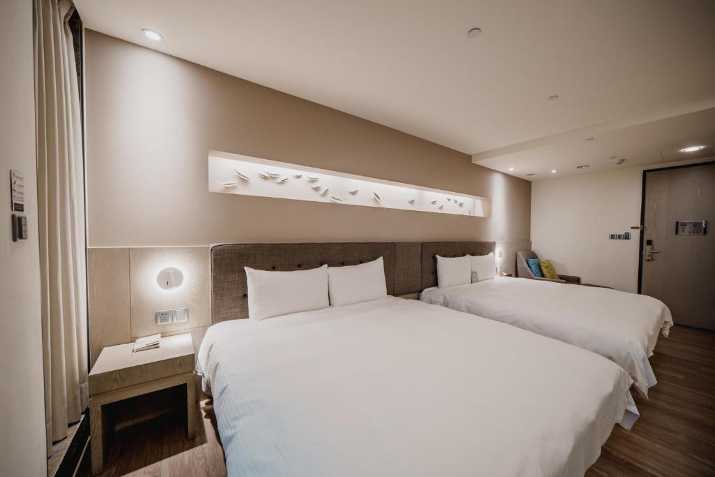 a hotel room with two beds with white sheets at Hub Hotel Kaohsiung Yawan Branch in Kaohsiung