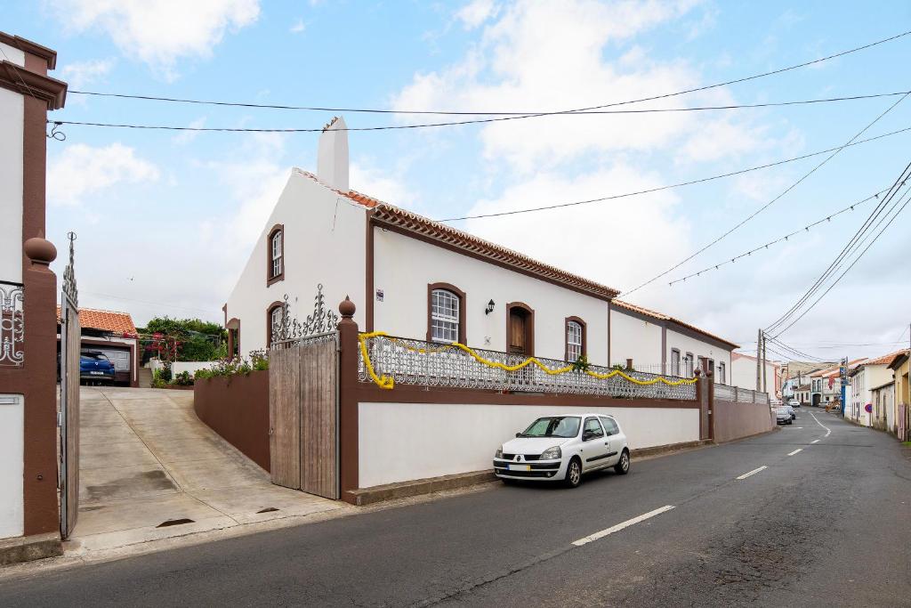 una macchina bianca parcheggiata di fronte a un edificio di Casa das Rosas ad Angra do Heroísmo