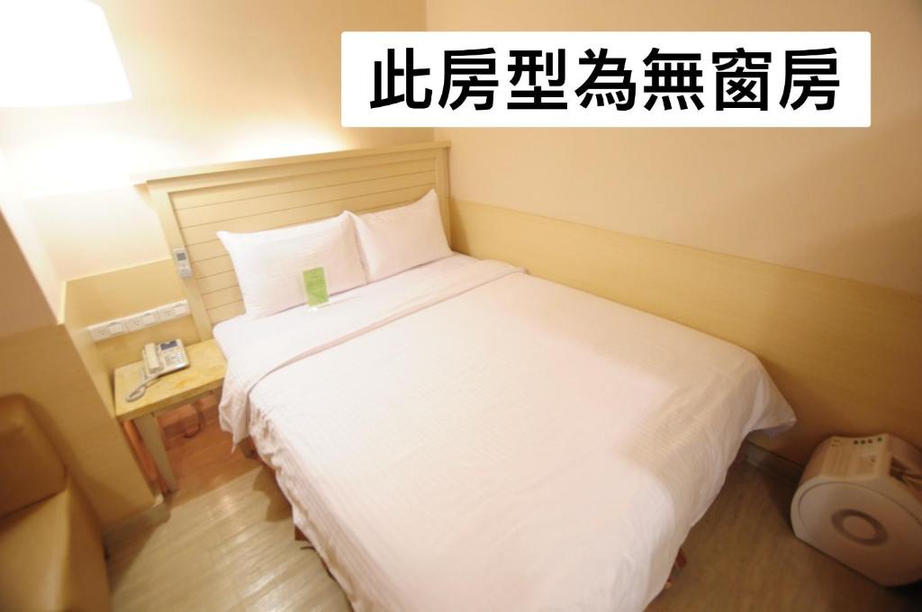 a bedroom with a large white bed in a room at Kindness Hotel - Tainan Minsheng in Tainan
