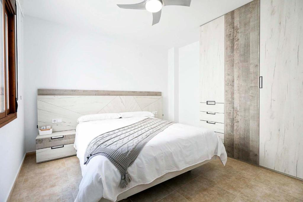 a white bedroom with a bed and a ceiling fan at Apartamento San Cristobal in Marbella